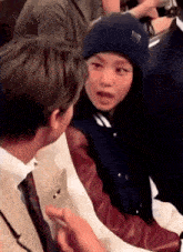 a man in a suit and tie is talking to a girl in a baseball jacket