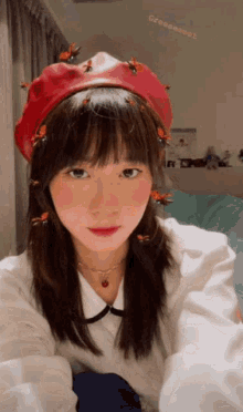 a girl wearing a red hat with bees on it takes a selfie
