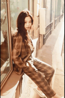 a woman in a plaid suit sits on a windowsill