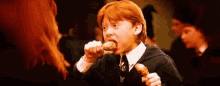 a young boy with red hair is eating a piece of food while a woman looks on .