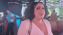 a woman in a white sweater is standing in a room