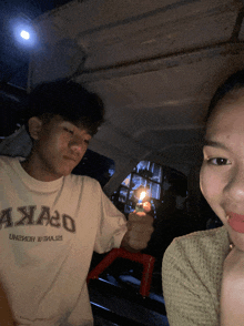 a man holding a lighter next to a woman wearing a shirt that says " axxao "