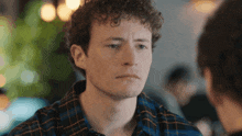 a young man with curly hair is sitting at a table with another man .
