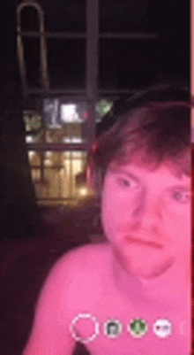 a man without a shirt is taking a picture of himself with a pink background .