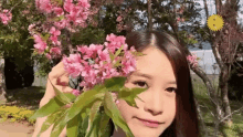 a woman is holding a flower in front of her face and smiling .