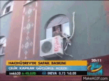 an air conditioner is hanging from the side of a building .