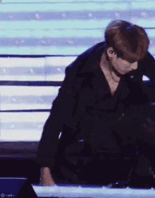 a man in a black suit is kneeling down on a stage