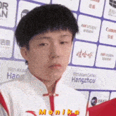 a young man is standing in front of a wall with signs that say hikvision and canon