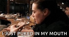 a woman is sitting at a table eating a piece of bread and says " i just puked in my mouth "