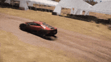 a red lamborghini is driving down a dirt road