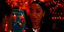 a woman is smiling in front of a christmas tree with red lights