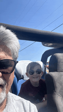 a man and a boy wearing sunglasses are sitting in the back seat of a car