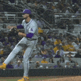 a baseball player in a purple and white uniform with the letter l on the back