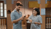 a man is looking at his phone while a woman holds a tray of food .