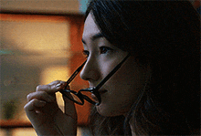 a woman adjusts her glasses while looking down