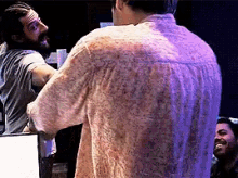a man with a beard is standing in front of a mirror and talking to another man .
