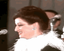 a woman is singing into a microphone while wearing a white feathered scarf around her neck