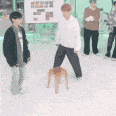 a group of young men are playing a game with a wooden stool .