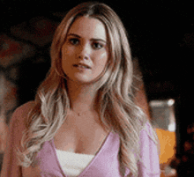 a woman is wearing a pink sweater and a white tank top .