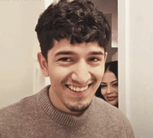 a man with curly hair and a beard smiles for the camera