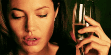 a woman is holding a glass of wine and drinking it .