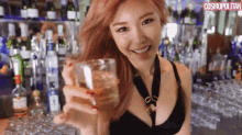 a woman is holding a glass of water in front of a bar .