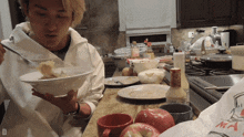 a person holding a bowl of food in a kitchen with a bag that says ' ma ' on it