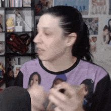 a woman wearing a purple shirt with a picture of a woman on it is sitting in front of a microphone .
