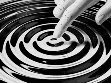 a black and white photo of a person 's hand touching a plate