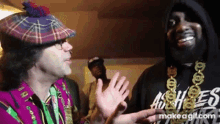 a man in a plaid hat is talking to another man in a black hoodie