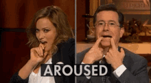 a man and a woman are making funny faces in front of a sign that says arused .