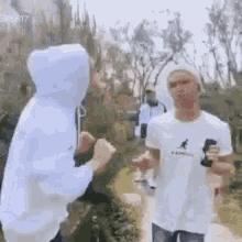 two men are standing next to each other in a park talking to each other .