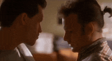 two men are looking at each other with their eyes closed in a room .