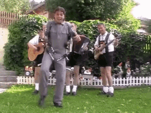 a group of men are playing instruments in a backyard and one of them is holding an accordion .