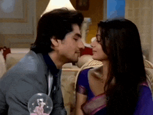 a man kisses a woman on the cheek in front of a snowglobe