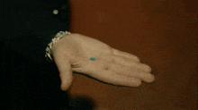 a man is holding a small blue pill in his hand
