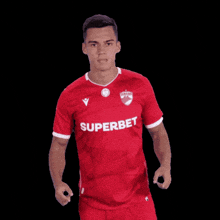 a man in a red superbet shirt points up