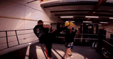 a man kicking another man in a boxing ring with the letter t on the back of his shirt