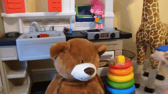 a teddy bear sits in front of a toy kitchen with a clock that says 8:20