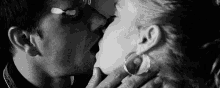 a man and a woman are kissing in a black and white photo . the woman is wearing hoop earrings .