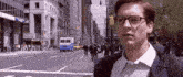 a man wearing glasses is standing on a city street