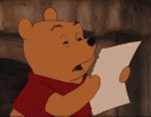 winnie the pooh is reading a piece of paper and making a funny face .