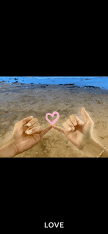 a couple making a pink heart with their fingers and the word love below them