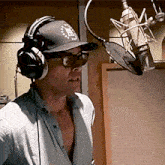 a man wearing headphones and a hat with the letter f on it is singing into a microphone