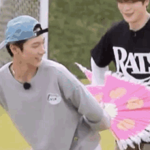 a man in a hat is holding a pink umbrella next to another man in a black shirt .