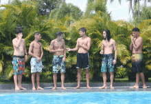 a group of young men are standing next to a swimming pool