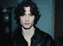 a young man with curly hair wearing a black jacket