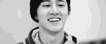 a black and white photo of a young man wearing a beret and a hoodie .