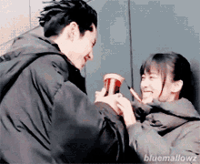 a man and a woman are standing next to each other and the man is giving the woman a cup of coffee .