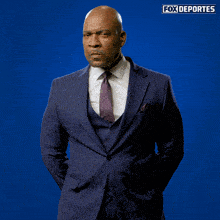 a man in a suit and tie holds a smiley face in front of a fox deportes logo
